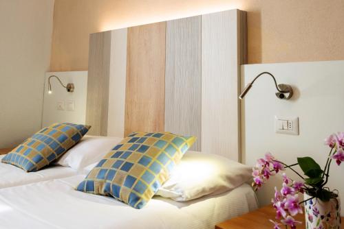 a bedroom with two beds with blue and yellow pillows at Albergo Pesce D'oro in Verbania