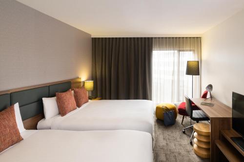 a hotel room with two beds and a desk at Novotel Sydney International Airport in Sydney