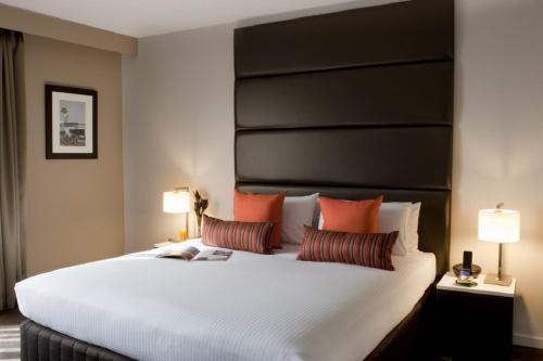 a bedroom with a large white bed with orange pillows at Novotel Sydney International Airport in Sydney
