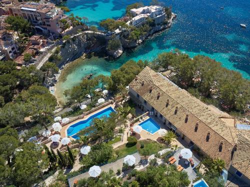 an aerial view of a resort with a pool and the ocean at Hotel Petit Cala Fornells in Paguera