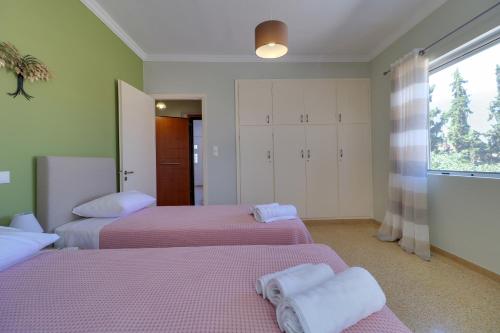 a bedroom with two beds and a window at Carpe Diem near the Athens airport in Markopoulo