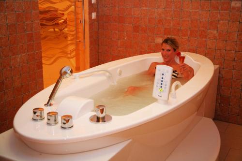 a woman sitting in a bath tub with a controller at Hotel Restaurant Marko in Velden am Wörthersee