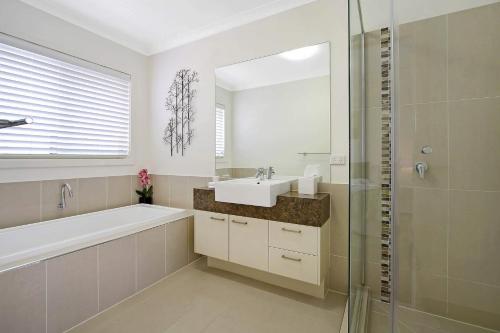 a bathroom with a sink and a tub and a mirror at The Grand Holiday House in Yarrawonga