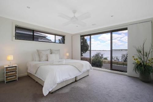 a white bedroom with a large bed and large windows at The Grand Holiday House in Yarrawonga