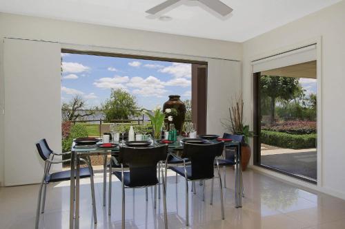 a dining room with a table and chairs and a large window at The Grand Holiday House in Yarrawonga