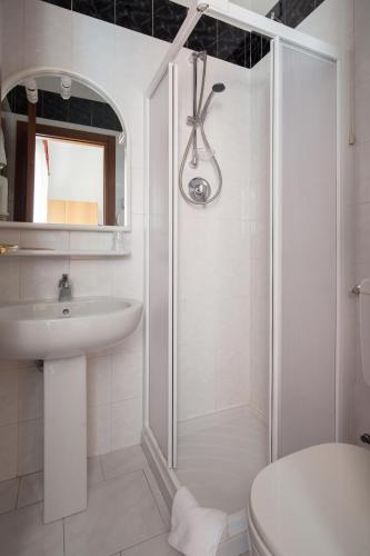 a white bathroom with a shower and a sink at Hotel Nella in La Spezia