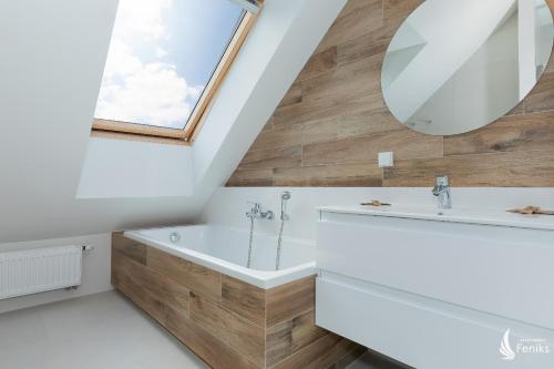 ein Badezimmer mit einem großen Spiegel und einer Badewanne in der Unterkunft Feniks Apartamenty - Baltic Summer SPA in Kołobrzeg