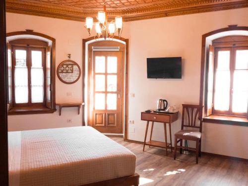 a bedroom with a bed and two windows and a table at Argjiro Traditional in Gjirokastër