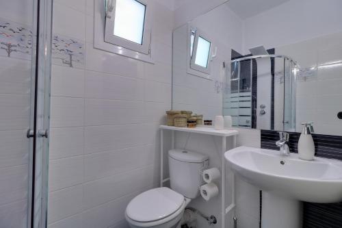a white bathroom with a toilet and a sink at Carpe Diem near the Athens airport in Markopoulo