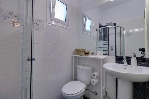 a white bathroom with a toilet and a sink at Carpe Diem near the Athens airport in Markopoulo