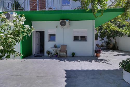 a white and green house with a table and chairs at Carpe Diem near the Athens airport in Markopoulo