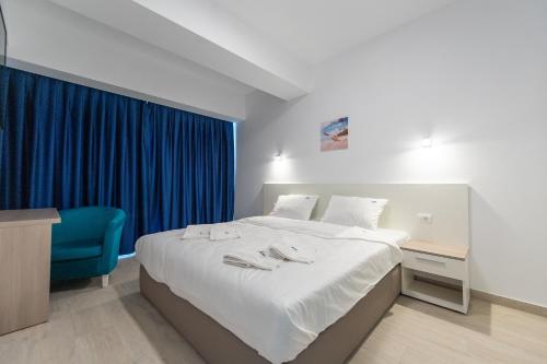 a bedroom with a large bed and a blue chair at ZIP Apartments in Mamaia