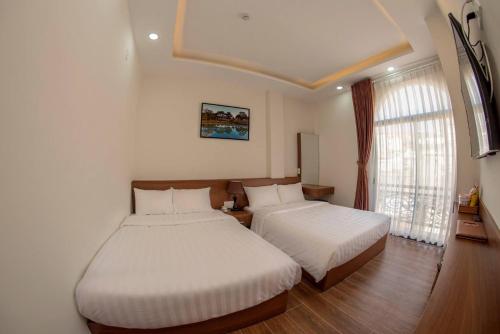 a bedroom with two beds and a window at Khánh Minh Hotel in Da Lat