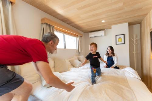 a man and a child jumping on a bed at Sakura Cross Hotel Shinjuku East in Tokyo