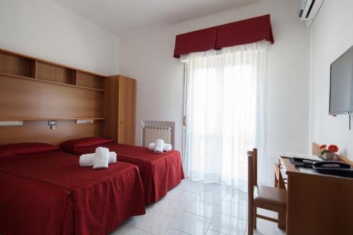 a bedroom with two beds with red sheets and white towels at Hotel Nella in La Spezia