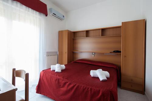 a bedroom with a red bed with two towels on it at Hotel Nella in La Spezia