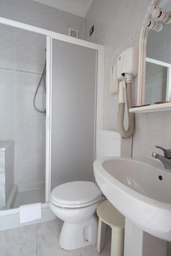 a white bathroom with a toilet and a sink at Hotel Nella in La Spezia