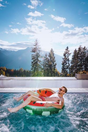 a man laying on an inner tube in a swimming pool at NIDUM - Casual Luxury Hotel in Seefeld in Tirol