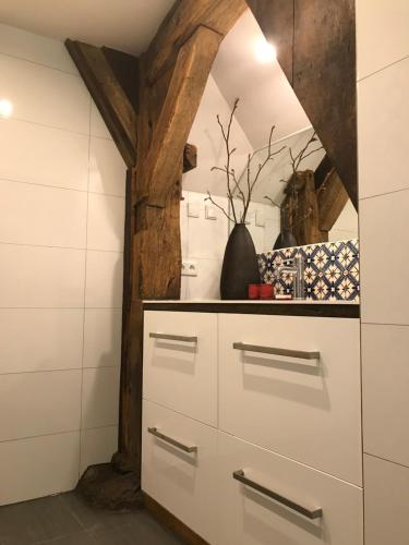 a kitchen with white cabinets and a stone wall at Op 't Oorbeck in Enschede