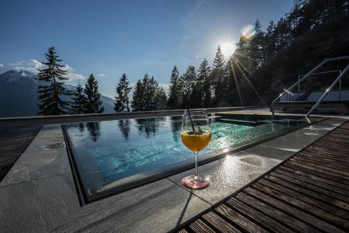 a glass of wine sitting on a table next to a pool at NIDUM - Casual Luxury Hotel in Seefeld in Tirol