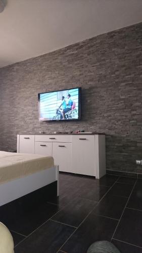 a living room with a tv on a brick wall at Bungalow Thaï vip jacuzzi interne in Ngaparou