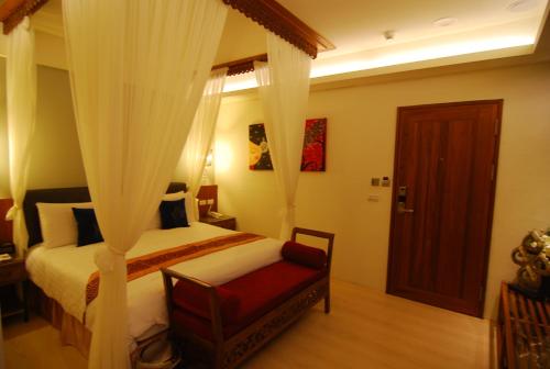 a bedroom with a bed with curtains and a chair at A&L Inn 戀灣旅棧 in Nanwan