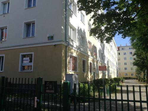un bâtiment jaune et blanc à côté d'une clôture dans l'établissement Apartament MINI CENTRUM, à Szczecin