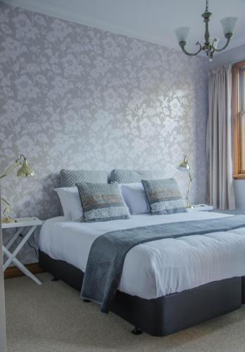 a bedroom with a king sized bed with a floral wallpaper at Mataura Lodge Athol in Athol