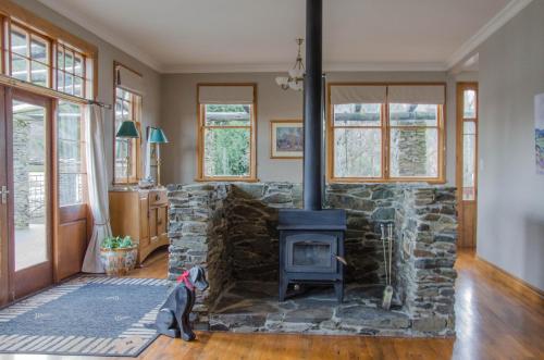 a stone fireplace in a living room with a stove at Mataura Lodge Athol in Athol