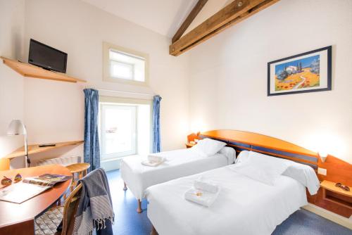 a hotel room with two beds and a table and a desk at LE SOUFFLE VERT in Cussac