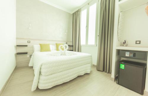 a white bedroom with a large bed with a ribbon on it at Hostal Pio Centro in Madrid