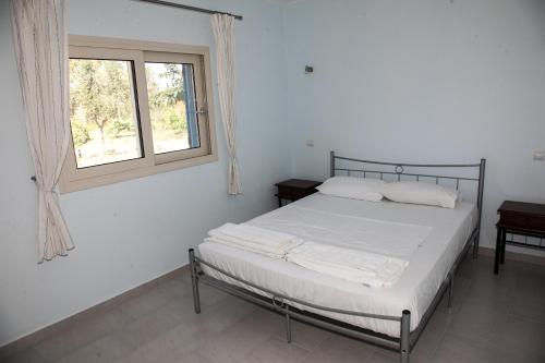 a white bedroom with a bed and a window at Romanos Xi in Xi