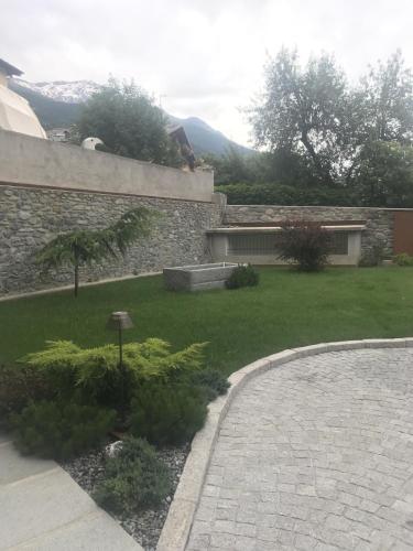 a backyard with a stone wall and a yard with plants at HOTEL AD Residence in Bormio