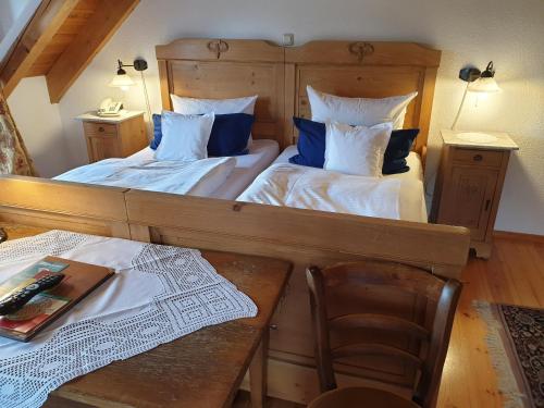 2 Betten in einem Zimmer mit einem Tisch und einem Stuhl in der Unterkunft CB Hotel Becker in Nieder-Olm