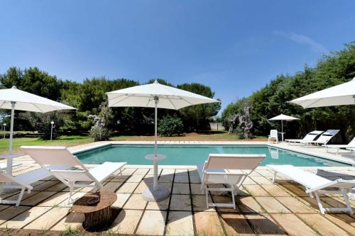 a pool with white chairs and umbrellas next to at Agriturismo Santa Chiara in Alezio