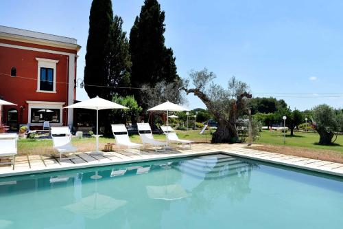 a swimming pool with chairs and umbrellas next to a house at Agriturismo Santa Chiara in Alezio
