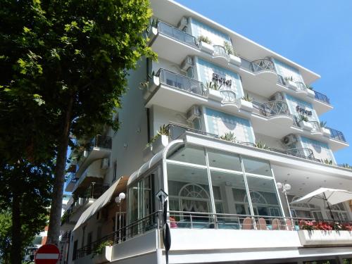 a white building with balconies and plants on it at Hotel Saponi in Rimini