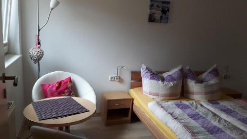 a bedroom with a bed and a chair with pillows at Ferienquartier Müller T6 in Trassenheide