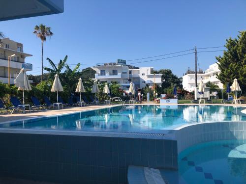 una gran piscina con sillas y sombrillas en Elpida Beach Studios en Faliraki