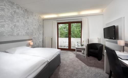 a hotel room with a bed and a desk and a television at Hotel des Nordens Flensburg Wellness & Spa in Flensburg