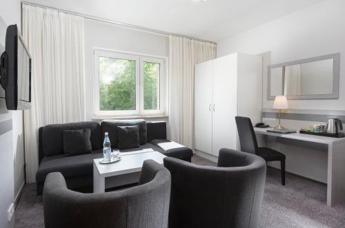 a living room with a couch and a table and chairs at Hotel des Nordens Flensburg Wellness & Spa in Flensburg