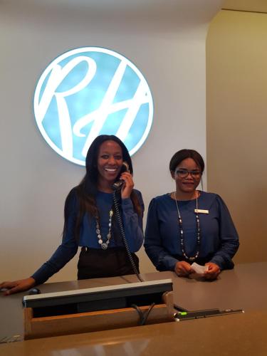 two women standing next to a table in front of a sign at RH Hotel & Apartments - Pretoria in Pretoria