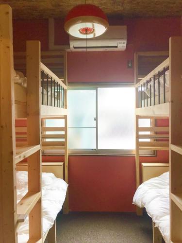 a room with two bunk beds and a window at Mad Cat Hostel Osaka & Bar in Osaka