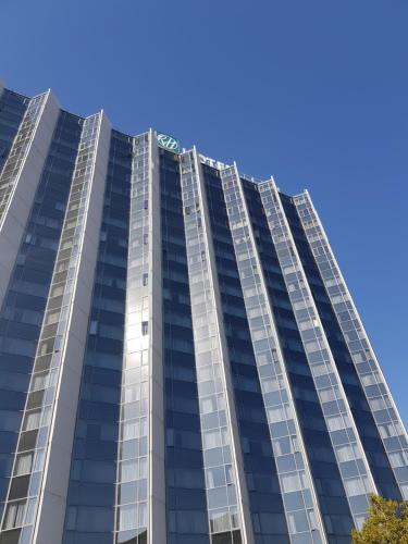 a tall glass building with a blue sky in the background at RH Hotel & Apartments - Pretoria in Pretoria