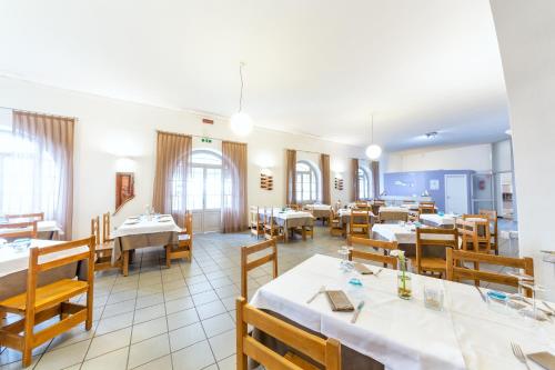 a restaurant with white tables and wooden chairs at Hotel Meli in Castelsardo