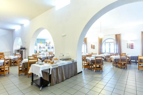 a restaurant with white tables and chairs and an archway at Hotel Meli in Castelsardo