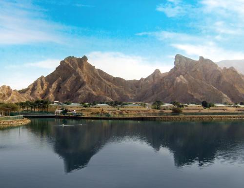 a body of water with mountains in the background at Green Mubazzarah Chalets in Al Ain