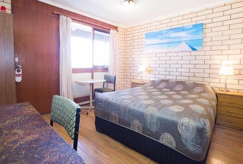 a bedroom with a bed and a table and a window at Augusta Budget Motel in Port Augusta