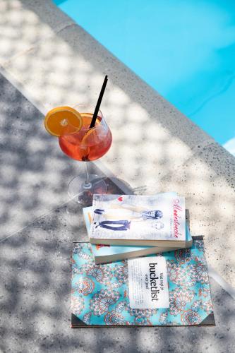 a drink and a book on a table next to a book at Racconto Boutique Design Hotel (Adults Only) in Parga