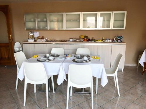 a dining room with a table and white chairs at Appartamenti Isola Verde in Villa